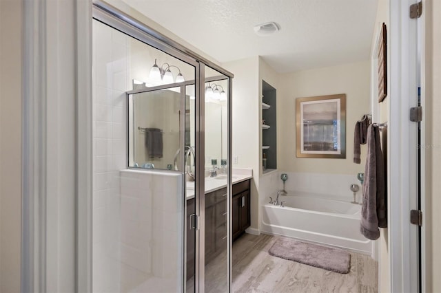 bathroom with hardwood / wood-style flooring, a textured ceiling, vanity, and shower with separate bathtub