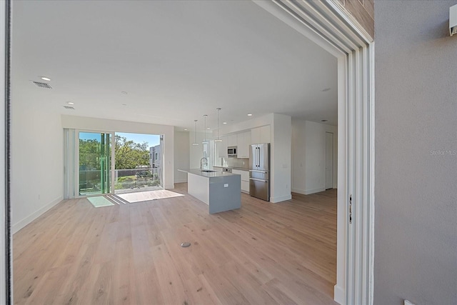 unfurnished living room featuring light hardwood / wood-style floors and sink