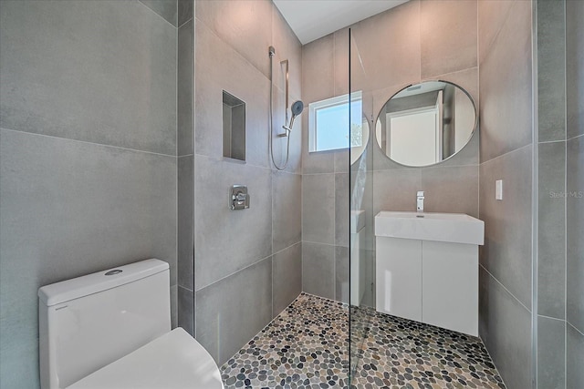 bathroom featuring tiled shower, vanity, toilet, and tile walls