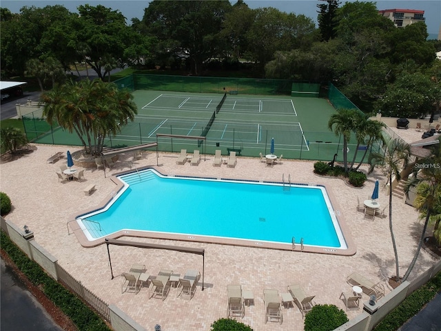 community pool featuring a tennis court, a patio, and fence