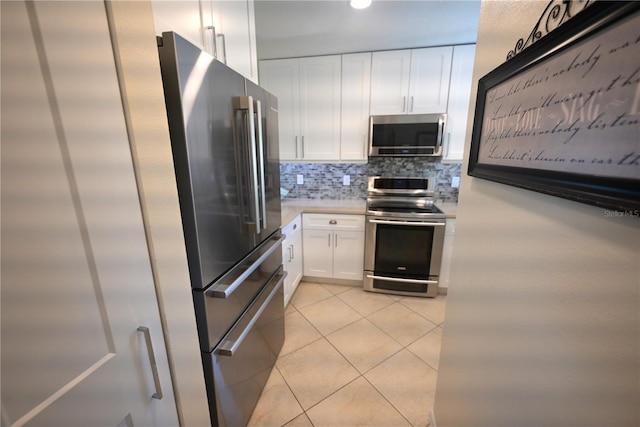 kitchen with decorative backsplash, white cabinets, appliances with stainless steel finishes, light countertops, and light tile patterned flooring