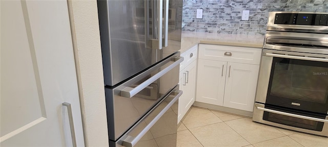 kitchen with tasteful backsplash, stainless steel electric stove, light countertops, fridge, and white cabinetry