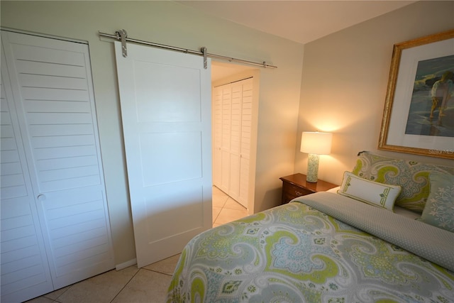 bedroom with light tile patterned floors and a barn door