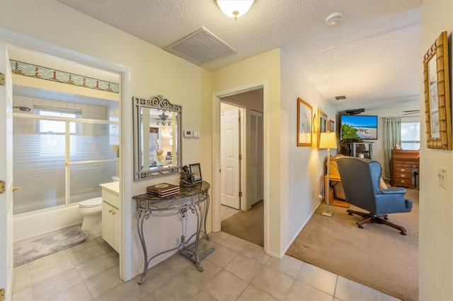 hallway with light colored carpet and a textured ceiling