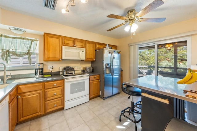 kitchen featuring a textured ceiling, white appliances, and ceiling fan