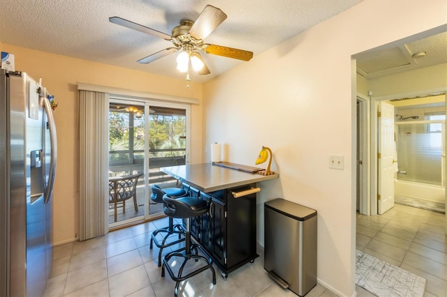 interior space with ceiling fan, light tile patterned flooring, and a textured ceiling