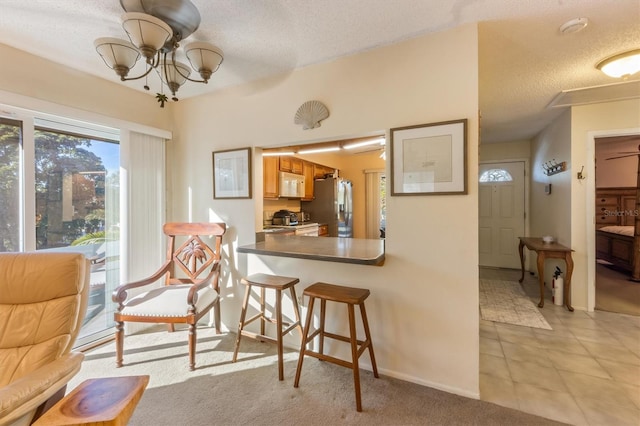 interior space featuring a chandelier, stainless steel fridge with ice dispenser, a textured ceiling, and light colored carpet