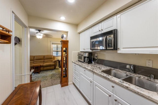 3511 Camino Real, Sarasota, FL 34239 - kitchen with stainless steel microwave, a sink, white cabinetry, a ceiling fan, and light stone countertops