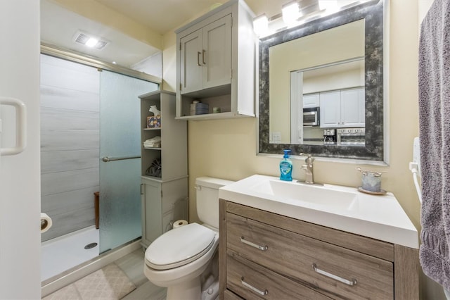 bathroom with vanity, toilet, and a shower with shower door