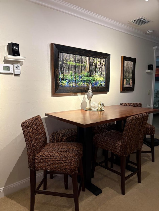 carpeted dining space with ornamental molding