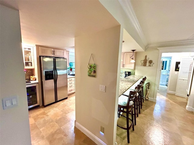 kitchen featuring wine cooler, stainless steel fridge, ornamental molding, and light brown cabinets