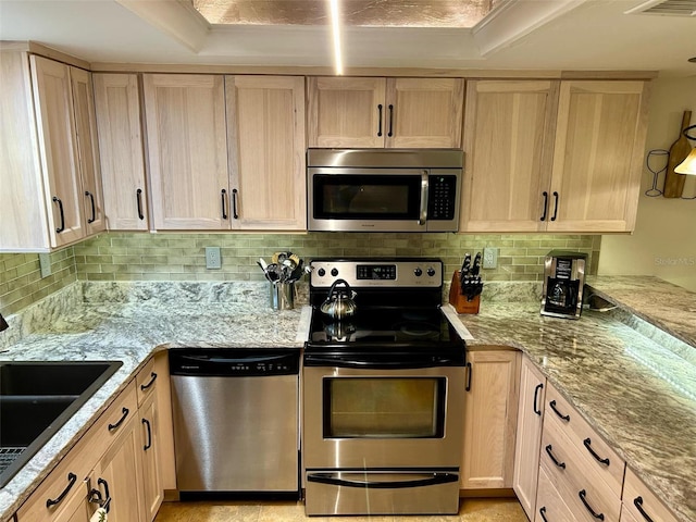 kitchen featuring light brown cabinets, backsplash, sink, appliances with stainless steel finishes, and a tray ceiling