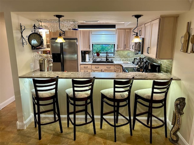 kitchen featuring light brown cabinets, sink, decorative light fixtures, decorative backsplash, and appliances with stainless steel finishes