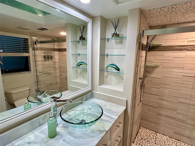 bathroom with tile patterned floors, vanity, toilet, and a tile shower