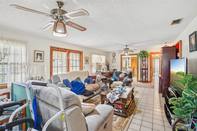 living room featuring light tile patterned floors, a textured ceiling, and ceiling fan