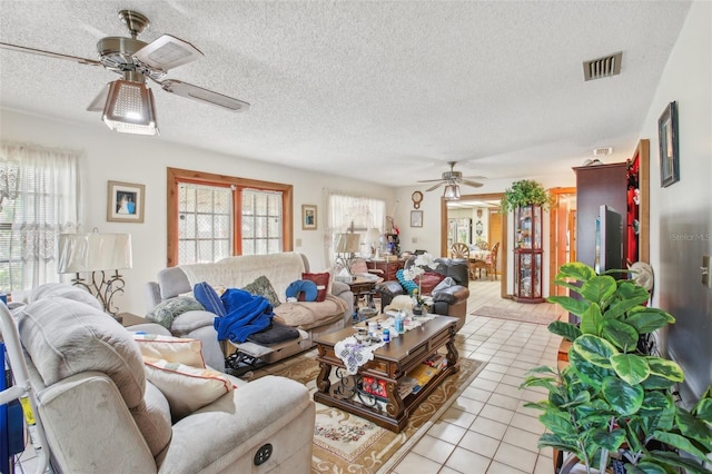 living room featuring ceiling fan, light tile patterned flooring, and a textured ceiling