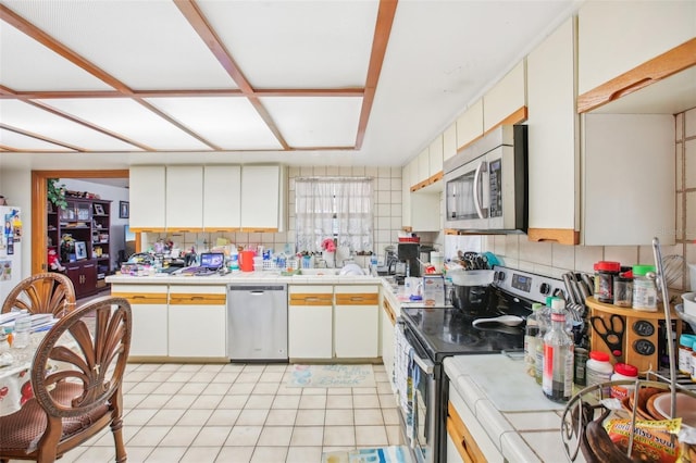 kitchen with decorative backsplash, white cabinetry, and stainless steel appliances