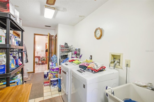 washroom with separate washer and dryer, sink, light tile patterned floors, and a textured ceiling