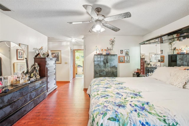 bedroom with ceiling fan, hardwood / wood-style floors, and a textured ceiling