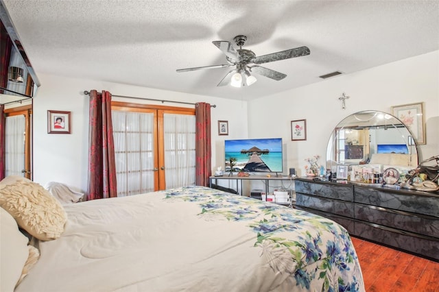 bedroom featuring ceiling fan, wood-type flooring, and a textured ceiling