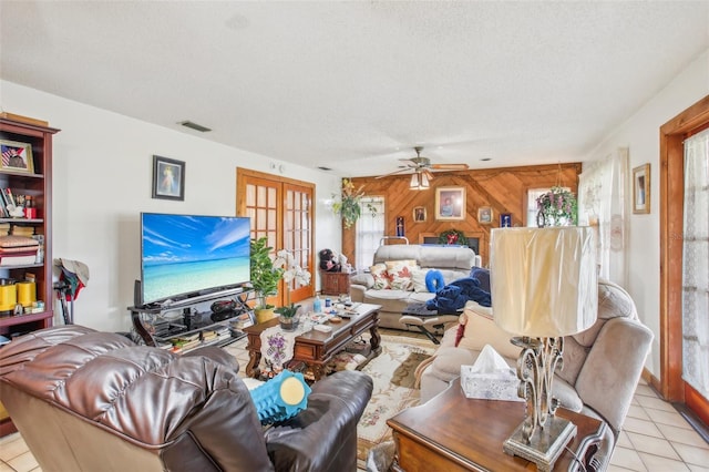 living room featuring ceiling fan, wood walls, a healthy amount of sunlight, and a textured ceiling