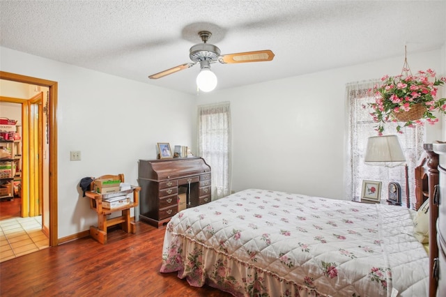 bedroom with a textured ceiling, dark hardwood / wood-style flooring, and ceiling fan