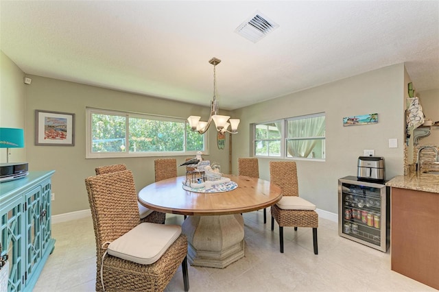 dining room featuring a chandelier, sink, beverage cooler, and a textured ceiling