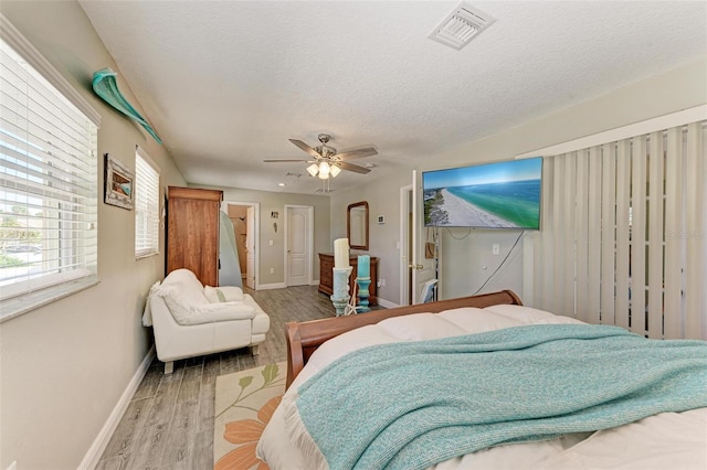 bedroom with a textured ceiling, light hardwood / wood-style floors, and ceiling fan