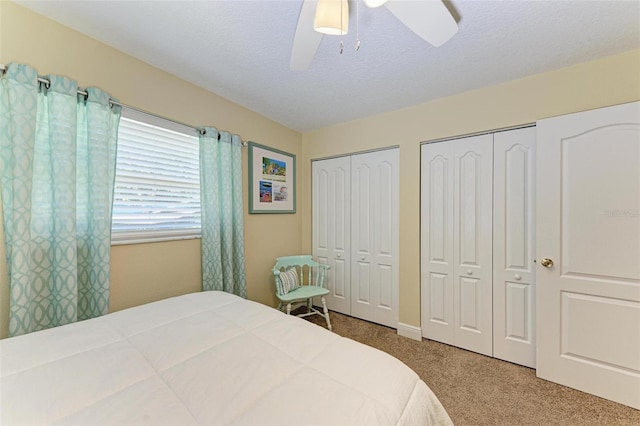 carpeted bedroom featuring multiple closets, ceiling fan, and a textured ceiling