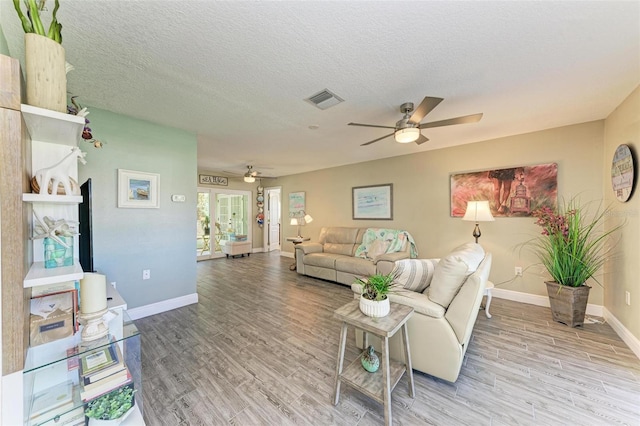 living room featuring light wood finished floors, baseboards, a ceiling fan, and visible vents