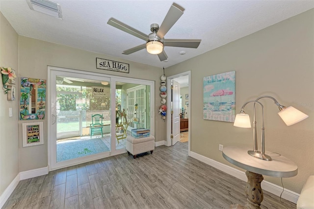 interior space featuring visible vents, wood finished floors, baseboards, and a ceiling fan