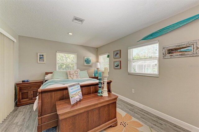 bedroom with a textured ceiling, light wood-type flooring, baseboards, visible vents, and recessed lighting