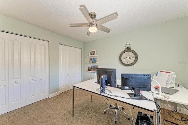 carpeted office space with a textured ceiling, baseboards, and ceiling fan