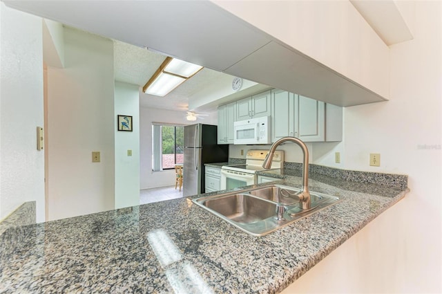 kitchen featuring white appliances, sink, ceiling fan, light tile patterned floors, and kitchen peninsula