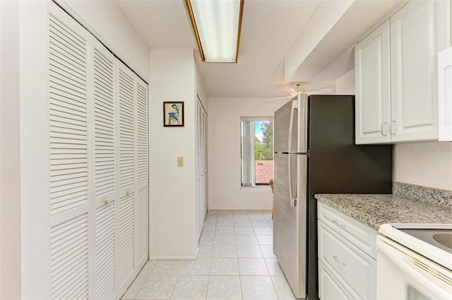 kitchen with light tile patterned floors, white cabinetry, ceiling fan, and light stone counters