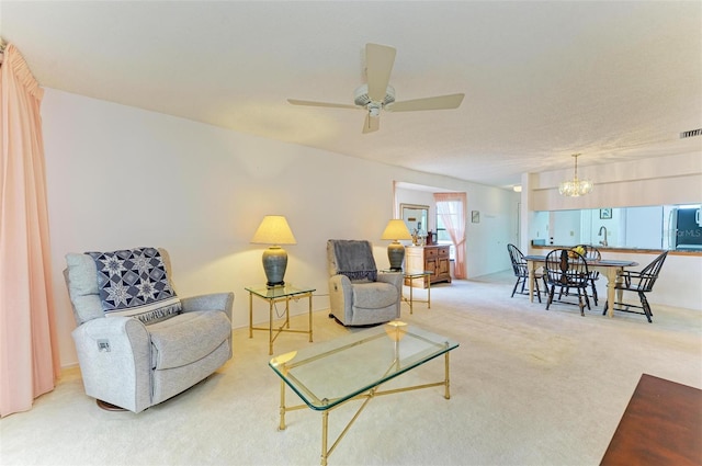 carpeted living room with ceiling fan with notable chandelier