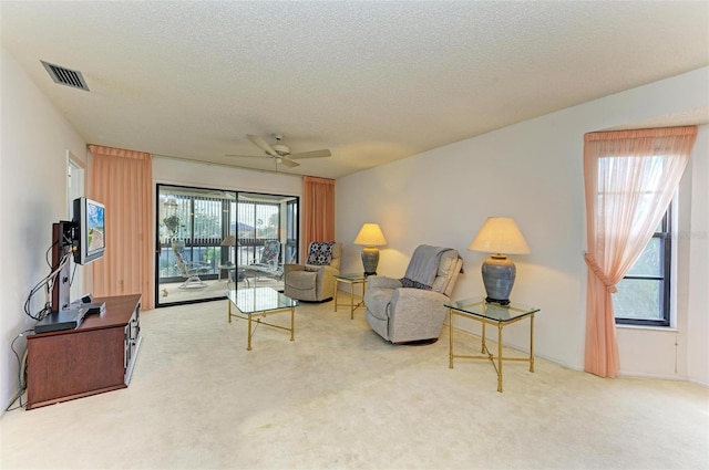 living room featuring ceiling fan, carpet floors, a healthy amount of sunlight, and a textured ceiling