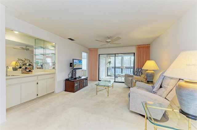 living room featuring light carpet, sink, and ceiling fan