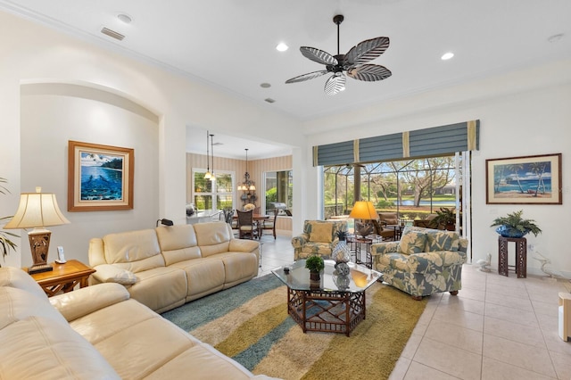 living room featuring ceiling fan, light tile patterned floors, a healthy amount of sunlight, and ornamental molding