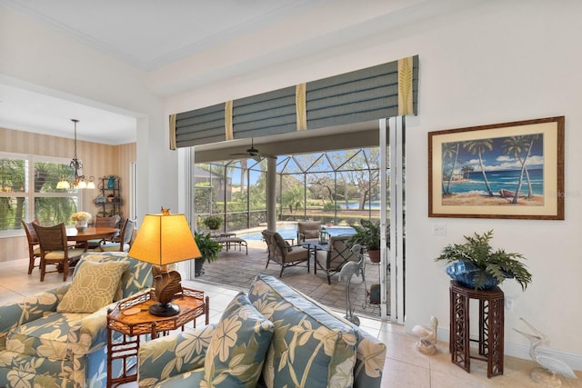 living room featuring ceiling fan with notable chandelier, a healthy amount of sunlight, light tile patterned floors, and crown molding