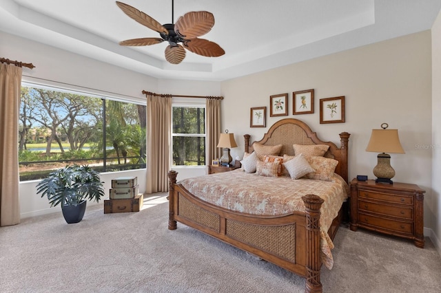 carpeted bedroom featuring a raised ceiling and ceiling fan