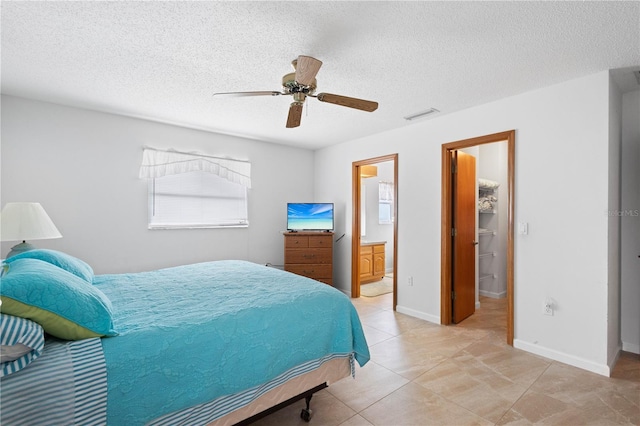 bedroom with a textured ceiling, ceiling fan, and ensuite bath