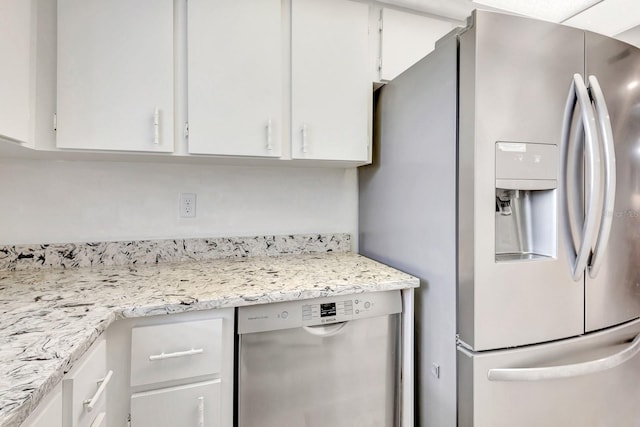 kitchen with white cabinets, appliances with stainless steel finishes, and light stone counters