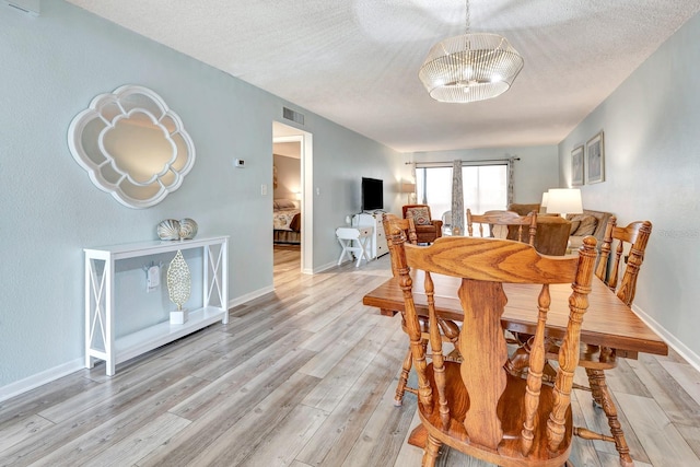 dining room featuring a chandelier, a textured ceiling, and light hardwood / wood-style floors