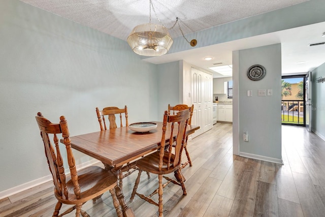 dining area featuring a textured ceiling and light hardwood / wood-style flooring