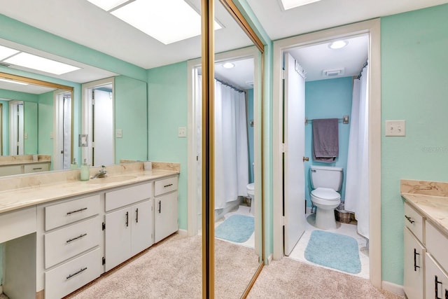 bathroom featuring toilet, vanity, and a skylight