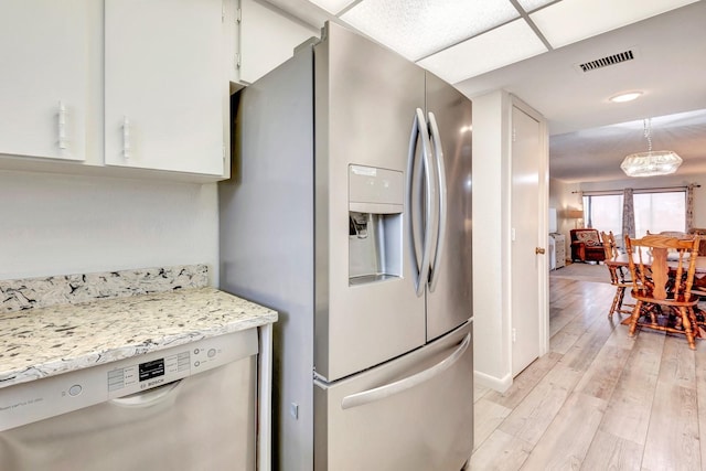 kitchen featuring light wood-type flooring, stainless steel appliances, white cabinets, and light stone counters