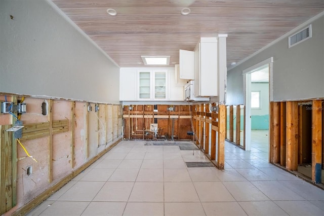 kitchen featuring white cabinets, wood walls, light tile patterned flooring, and wooden ceiling