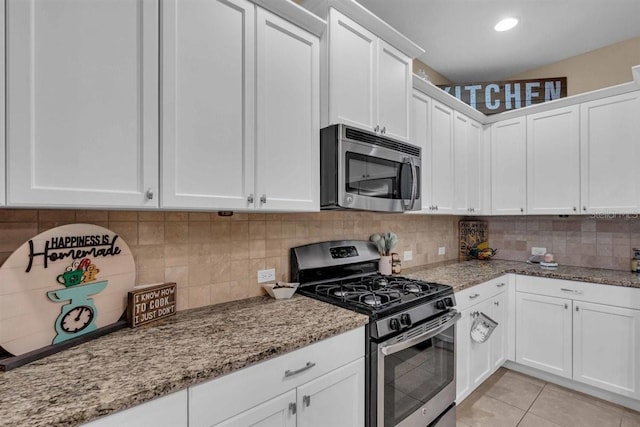 kitchen featuring light stone countertops, appliances with stainless steel finishes, white cabinetry, and light tile patterned flooring