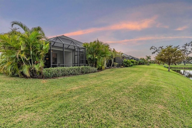 yard at dusk with a water view and a lanai